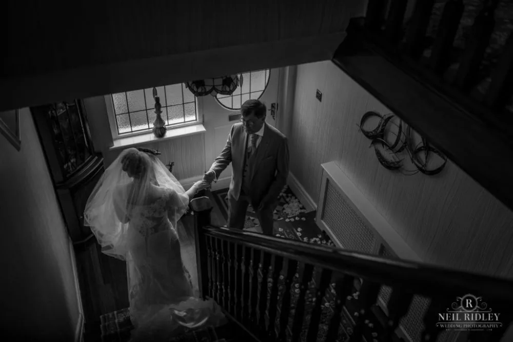 Black and white image of father seeing daughter for the first time in her wedding dress