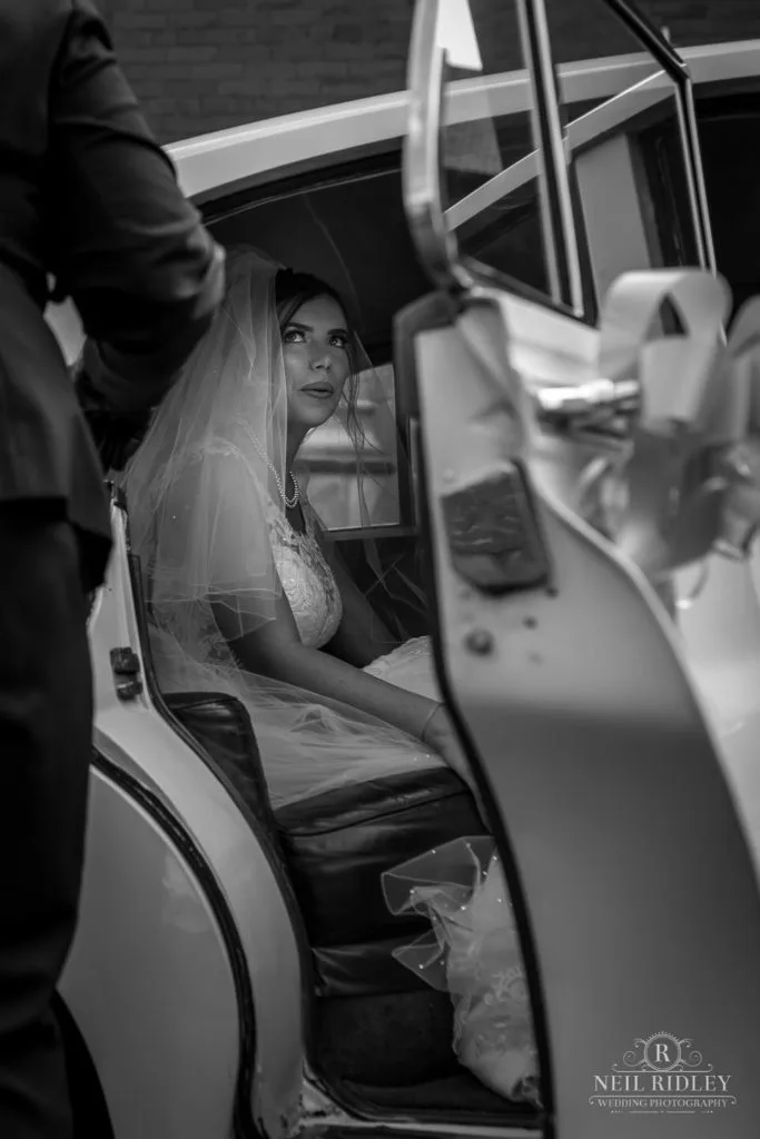Black and white image of bride in her car at St Thomas Church in St Annes-on-Sea