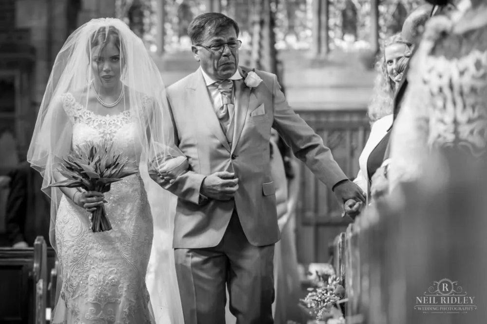 Black and white image of Bride and her Father walking down the aisle in church, with father crying at St Thomas Church in St Annes-on-Sea